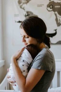 Image d'une maman apaisée avec son nouveau-né dans les bras pour illustrer que l'allaitement ne doit pas faire souffrir. 