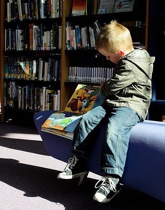Image représentant un petit garçon dyslexique dans une bibliothèque.