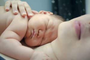 Photo représentant un bébé endormi contre sa mère en position de cododo. 