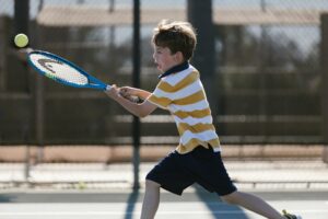 Photographie d'un enfant très motivé jouant au tennis. 